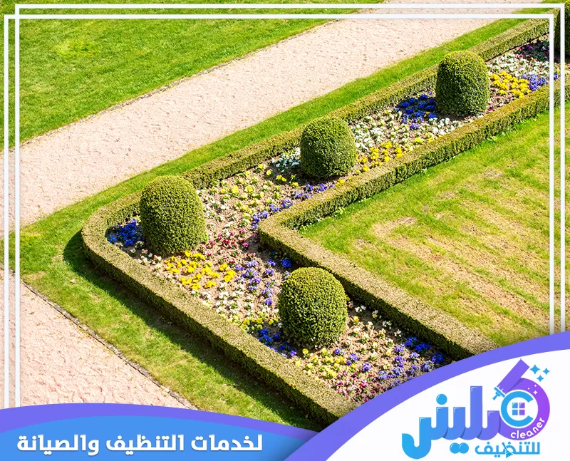 أحواض زهور ملونة تحيط بها سياجات نباتية مشذبة داخل حديقة منظمة