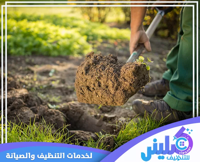 عامل يحفر التربة بالمجرفة لتجهيز مساحة زراعية داخل الحديقة