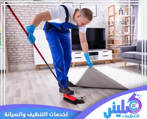 عامل تنظيف منازل بجدة يقوم بإزالة السجاد وتنظيف الأرضية في غرفة معيشة أنيقة. خدمات شركة كلينر للتنظيف بجدة 0500892799.