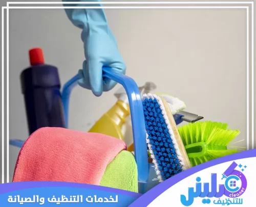 يحمل عامل تنظيف فلبيني في شركة كلينر للتنظيف 0500892799 حاوية مليئة بأدوات التنظيف الملونة، تشمل قماش وفرش.