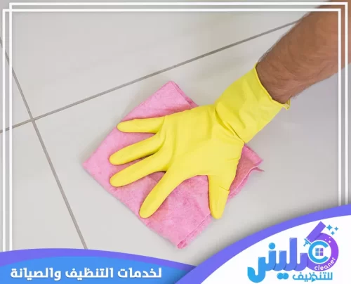 يد تستخدم قطعة قماش ناعمة لمسح الأرضيات، مع ارتداء قفازات صفراء. شركة كلينر للتنظيف هي الافضل في جدة 0500892799.
