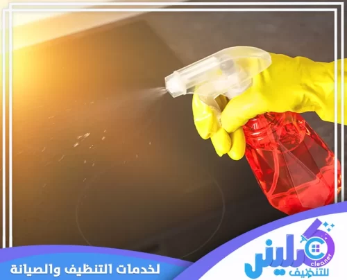فني متخصص من شركة كلينر 0500892799 لخدمات التنظيف والصيانة يقوم برش منظف على سطح مطبخ أسود لامع، مما يبرز فعالية الخدمة.