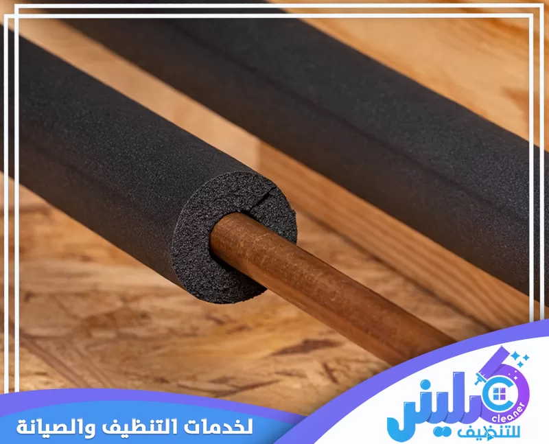 حجز عزل مواسير المياه بالرياض 0500892799 شركة كلينر. ماسورة نحاسية داخل عازل أسود على أرضية خشبية، مع ظهور لفائف عزل سوداء.
