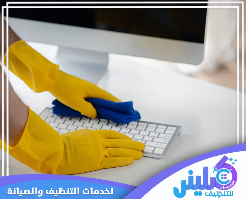تنظيف لوحة مفاتيح الكمبيوتر بعناية باستخدام قطعة قماش مخصصة داخل المكتب.