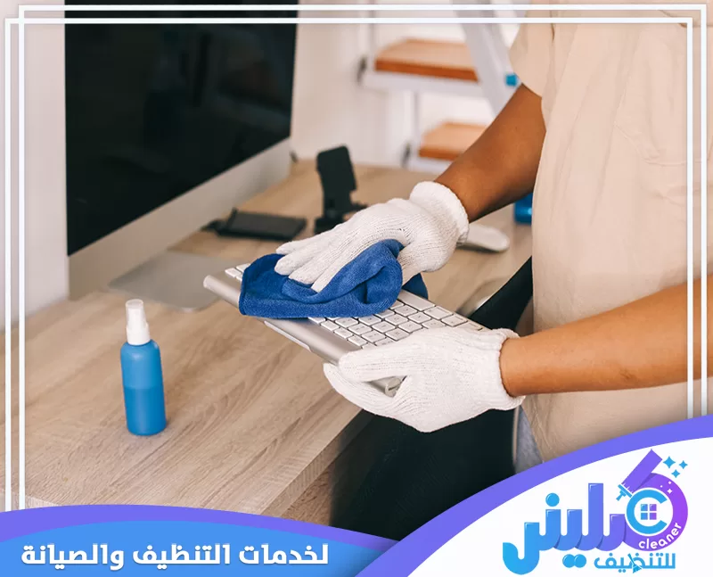 تنظيف معدات العمل المكتبية مع التركيز على لوحة المفاتيح والأسطح كثيرة الاستخدام.